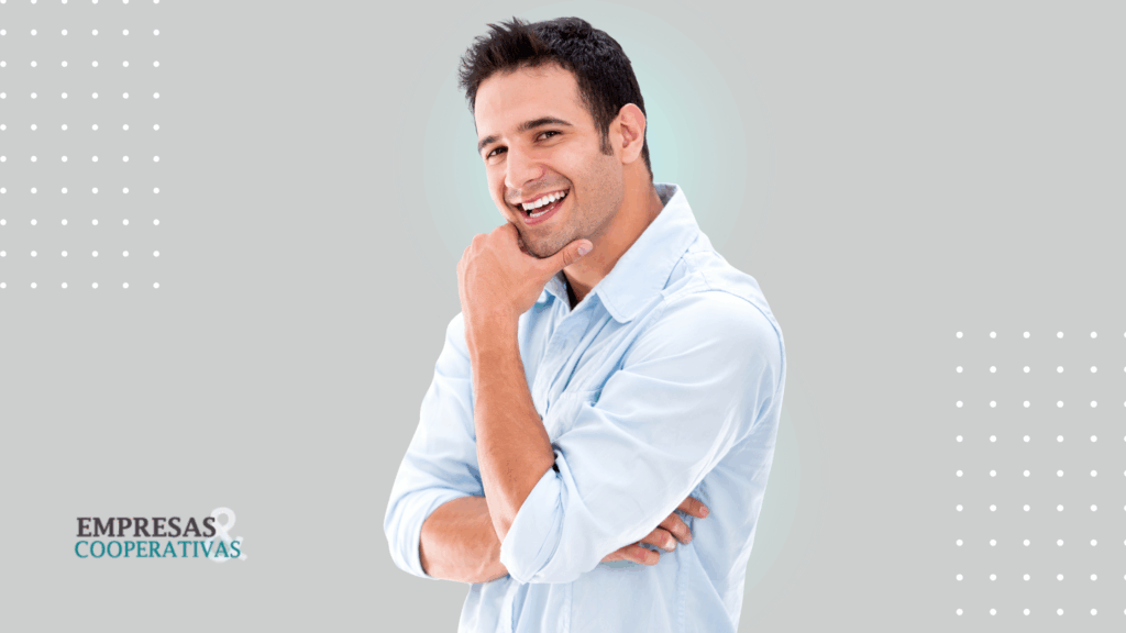 Homem branco, de camisa social azul clara, com a mão no rosto, sorridente.
