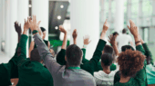 Uma assembleia com as pessoas com as mãos levantadas, votando